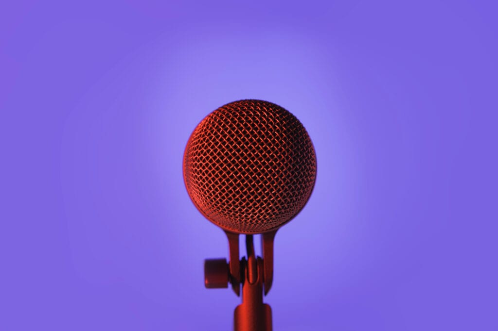 A podcast studio setup featuring a microphone on a vibrant purple background.