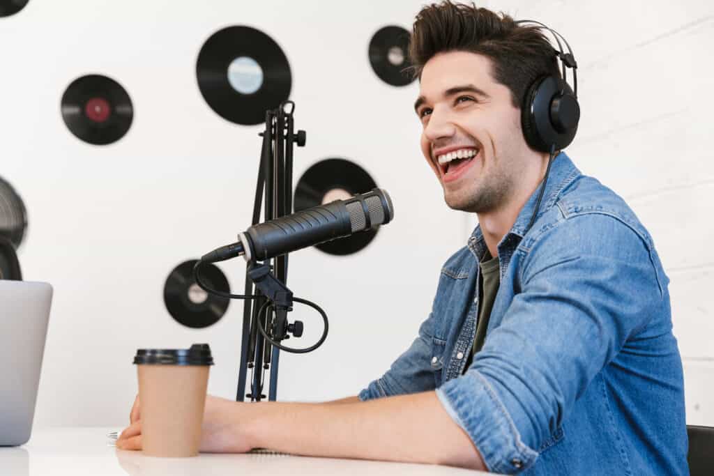 A man with headphones is sitting in front of a microphone in a podcast studio.