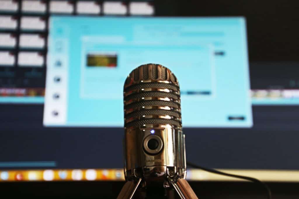 A podcasting microphone in front of a computer screen, symbolizing the business plan for a podcasting venture.