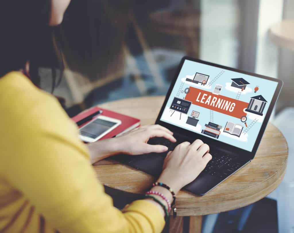 A woman using a laptop with the word "learning" on it to sell your courses online.
