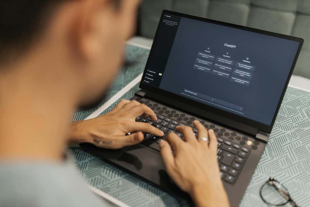 A man typing on a laptop computer, creating content for the best platform to sell online courses.