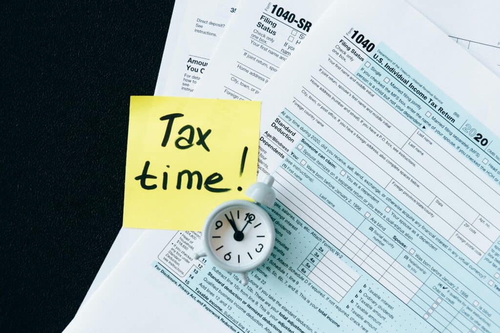 Alarm clock and a sticky note on tax forms signaling the approach of the tax filing deadline, reminding to differentiate active income vs passive income.